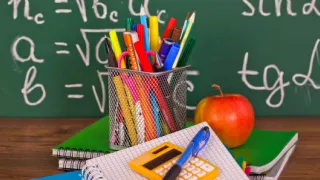 Des fournitures scolaires devant un tableau d'école
